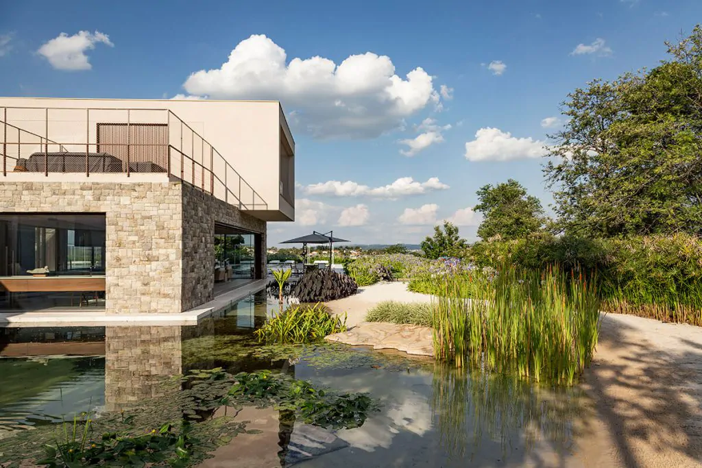 Arquitetura moderna em residência com plantas nativas e espaço de descanso.